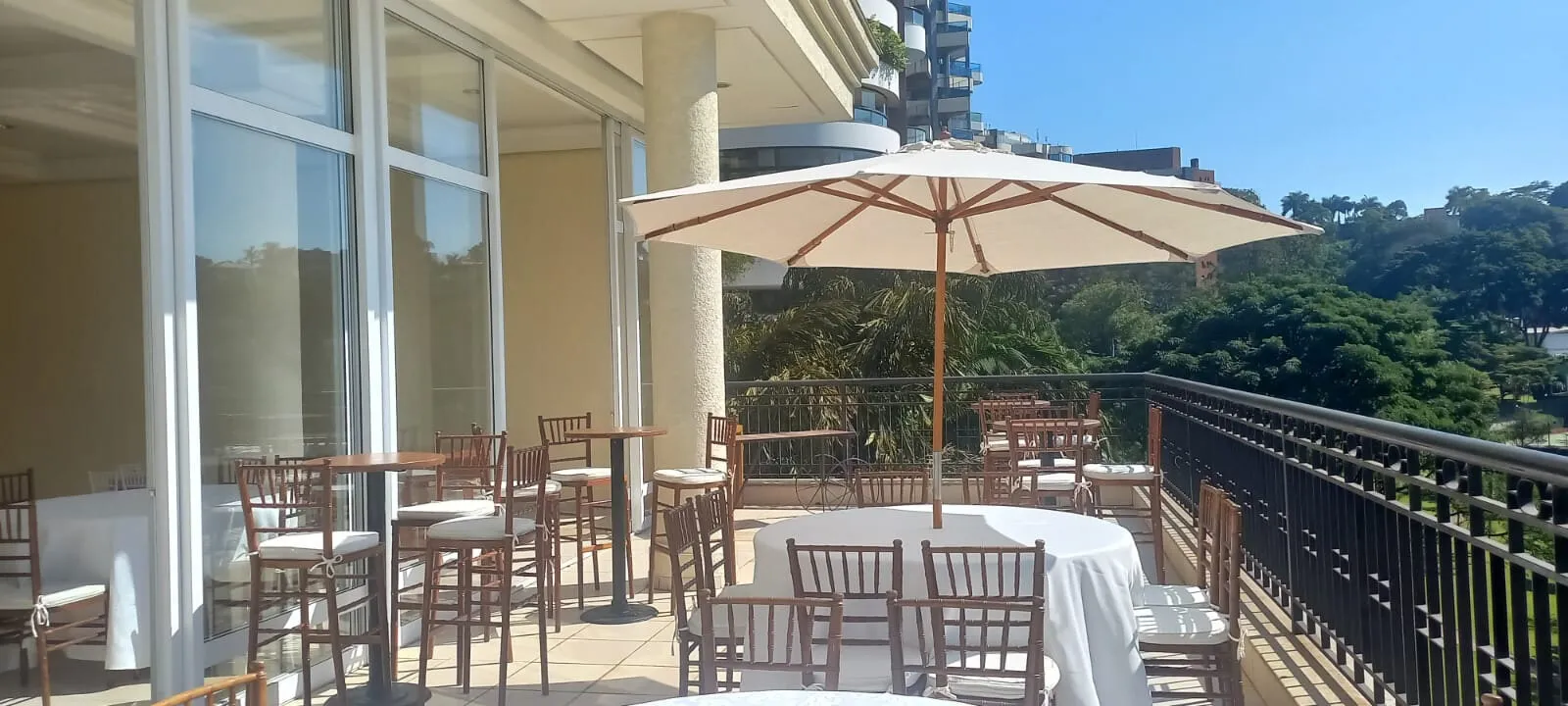 Ombrelone cru no terraço com bistrôs, Tiffany altas e toalha branca