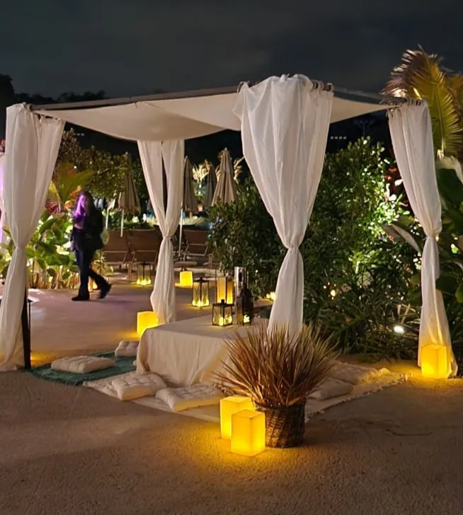 Gazebo com cortinas e almofadas futon à noite