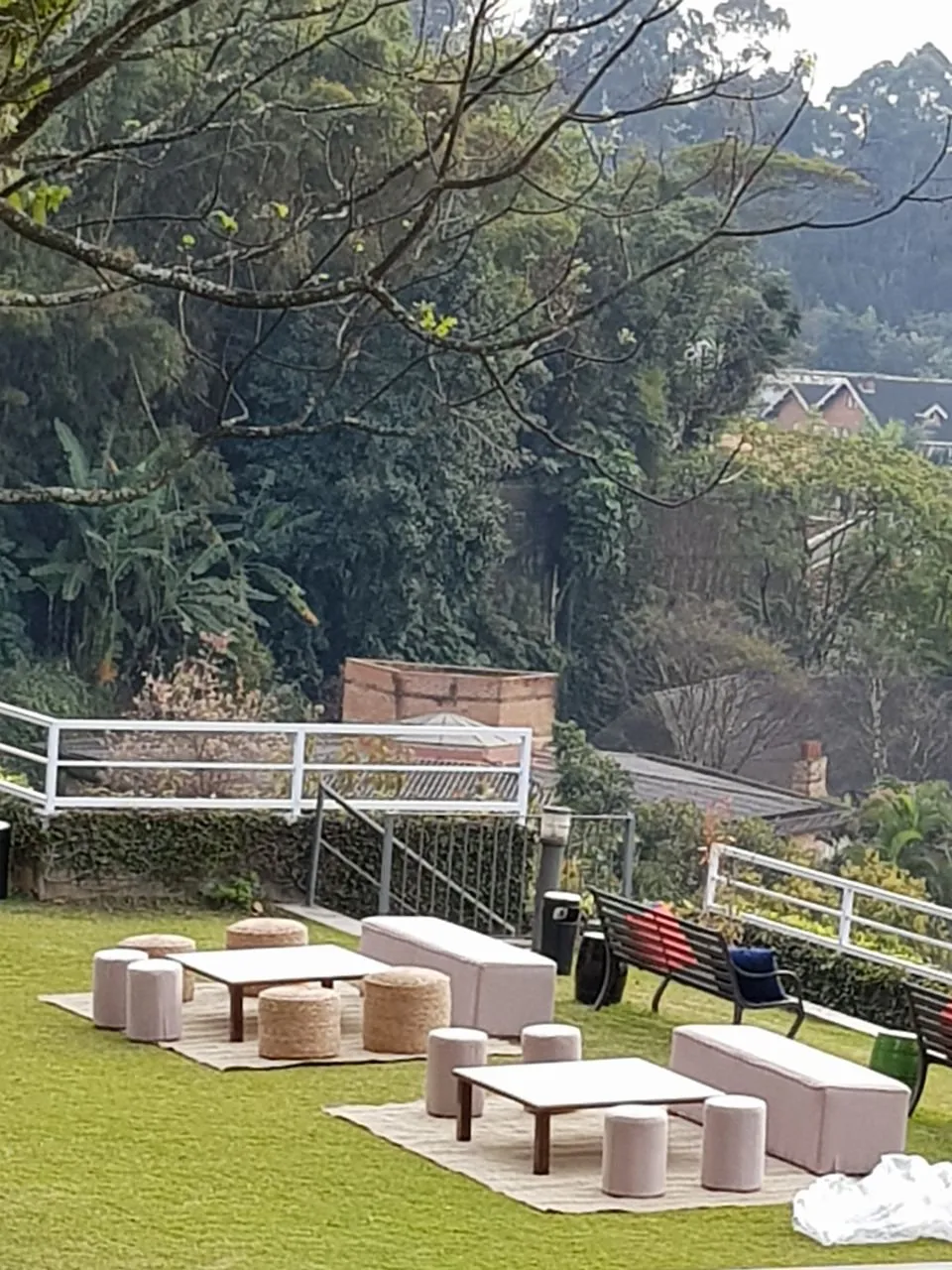 Lounge no gramado com pufes de palha e pufes brancos