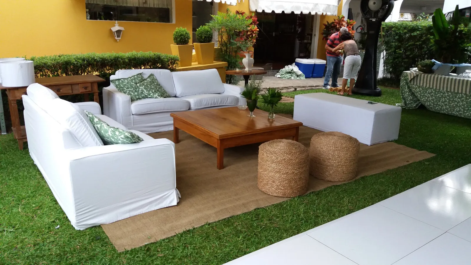 Lounge no jardim com sofás brancos e pufes de palha