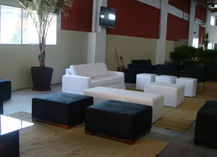 Lounge com pufes pretos, pufe longo branco e sofá branco
