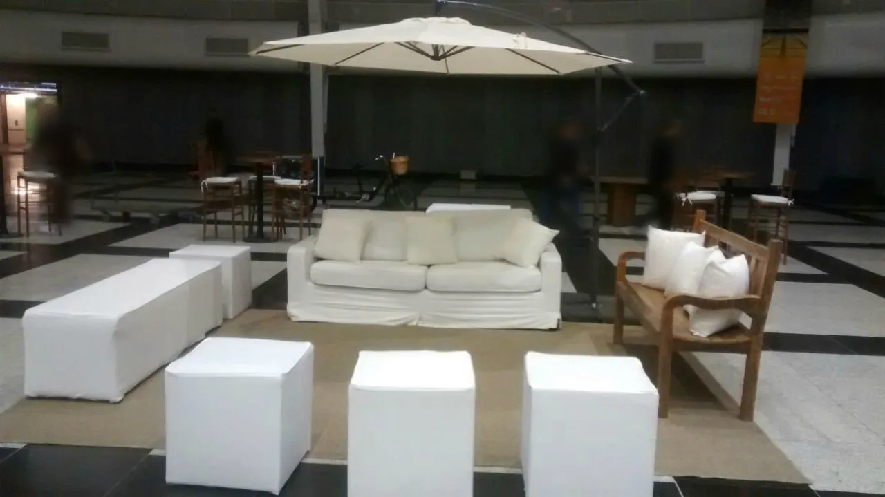 Lounge com ombrelone lateral, sofá branco e pufe longo