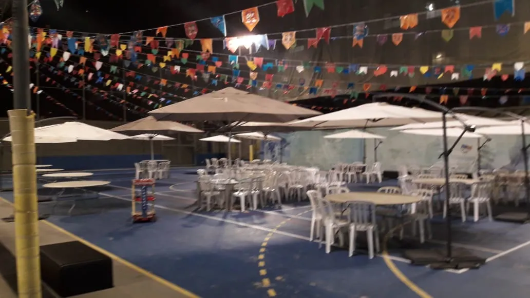 Ombrelones laterais e cadeiras plásticas em quadra à noite