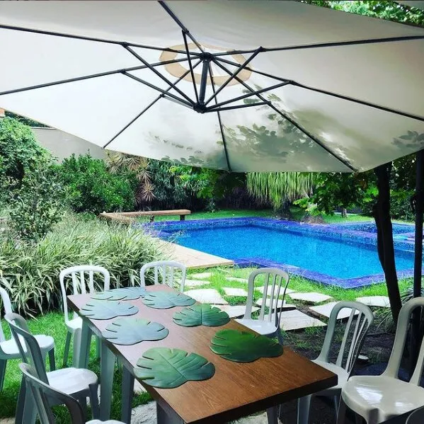 Ombrelone lateral e cadeiras plásticas brancas na piscina
