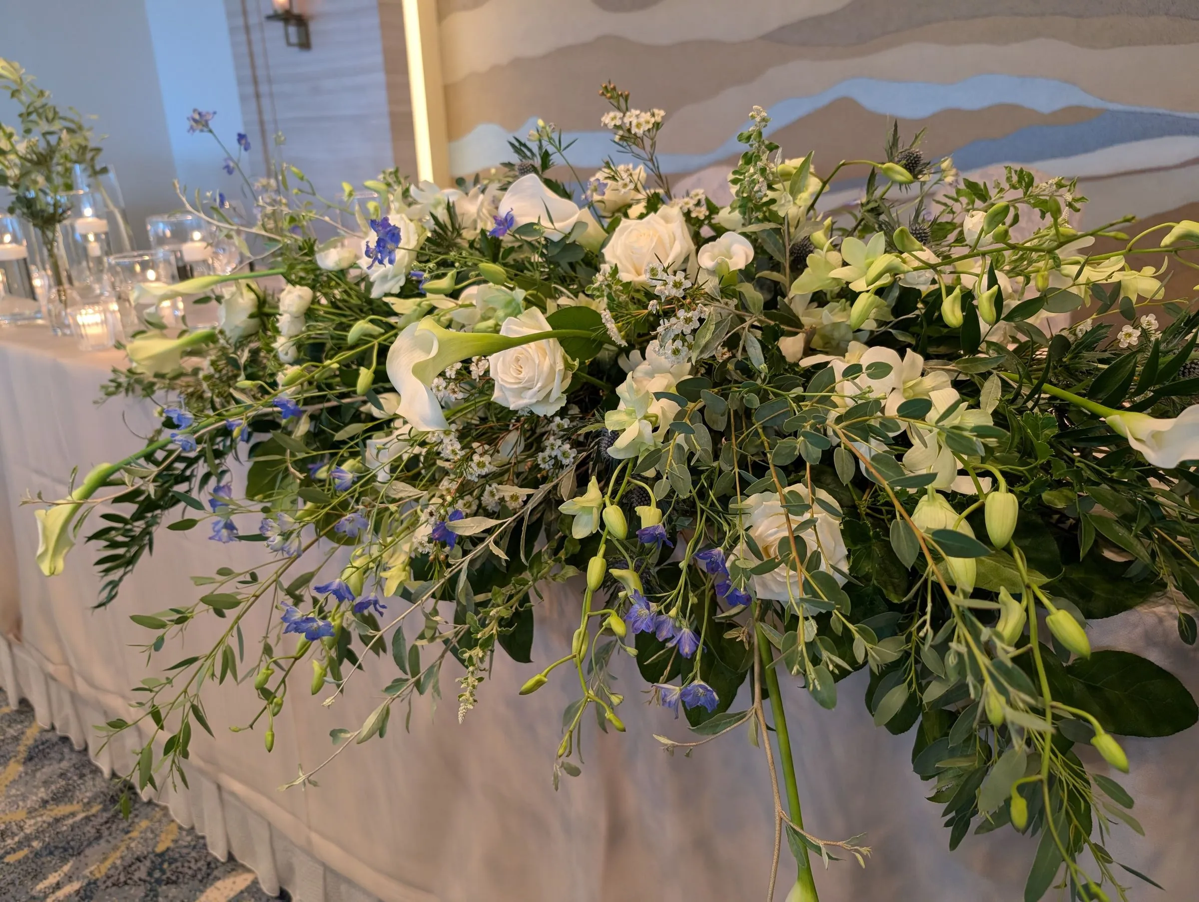 Arranjo longo de flores brancas e folhagens sobre a mesa